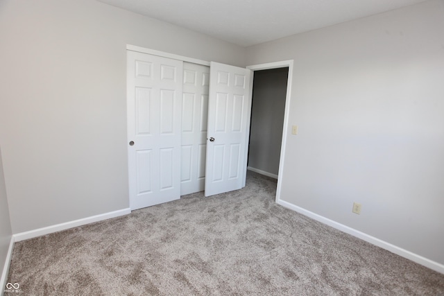 unfurnished bedroom with light colored carpet and a closet