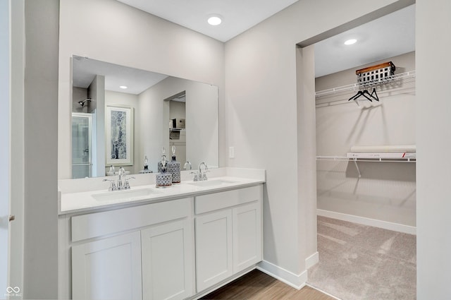 bathroom with hardwood / wood-style floors, vanity, and a shower with door