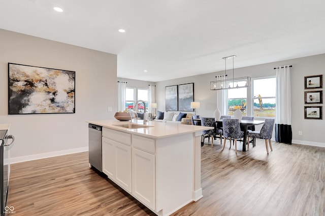 kitchen featuring white cabinets, sink, an island with sink, and plenty of natural light