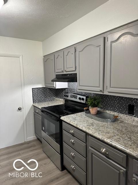 kitchen with light hardwood / wood-style flooring, backsplash, gray cabinets, a textured ceiling, and electric stove