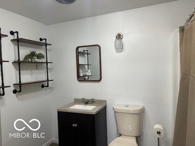 bathroom with curtained shower, vanity, and toilet