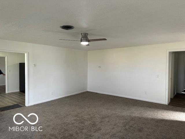 spare room with ceiling fan and dark colored carpet