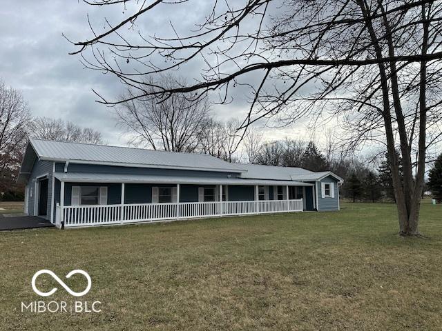 view of front of property featuring a porch, a garage, and a front lawn