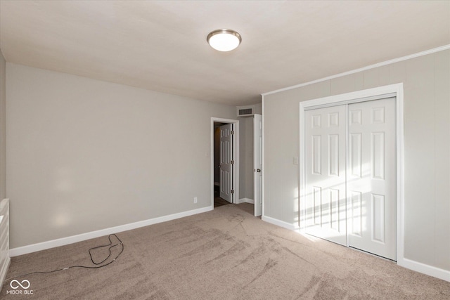 unfurnished bedroom with carpet, ornamental molding, and a closet