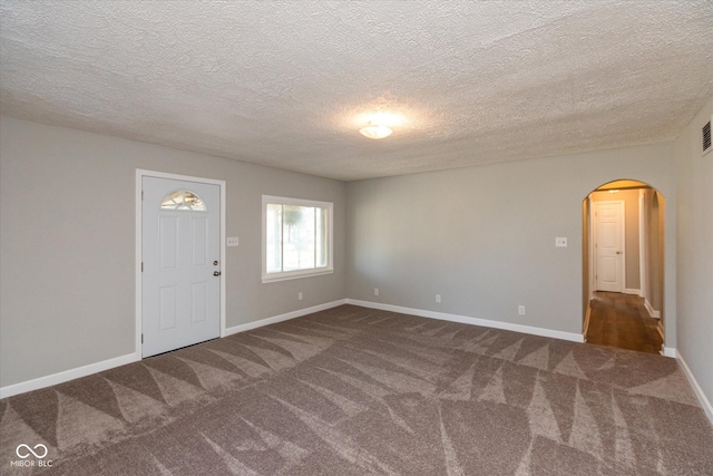 foyer with a textured ceiling and dark colored carpet