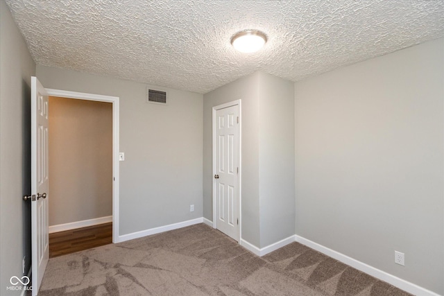 carpeted empty room featuring a textured ceiling