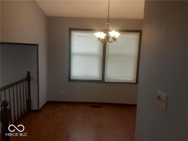 spare room featuring carpet and an inviting chandelier