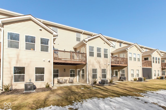 snow covered back of property featuring a patio area, a lawn, and central air condition unit