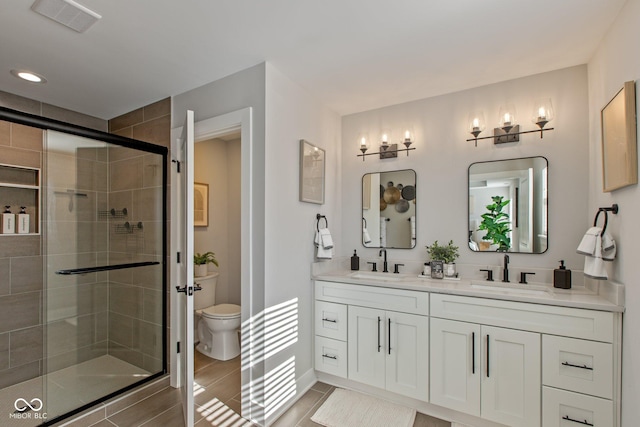 bathroom with vanity, a shower with shower door, and toilet