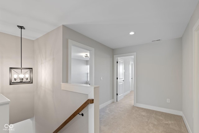 hall featuring light colored carpet and an inviting chandelier