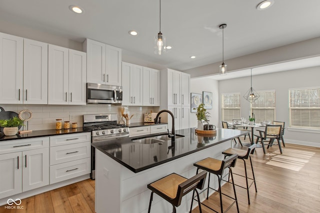 kitchen featuring pendant lighting, appliances with stainless steel finishes, sink, and a center island with sink