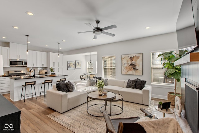 living room with sink, light hardwood / wood-style floors, and ceiling fan