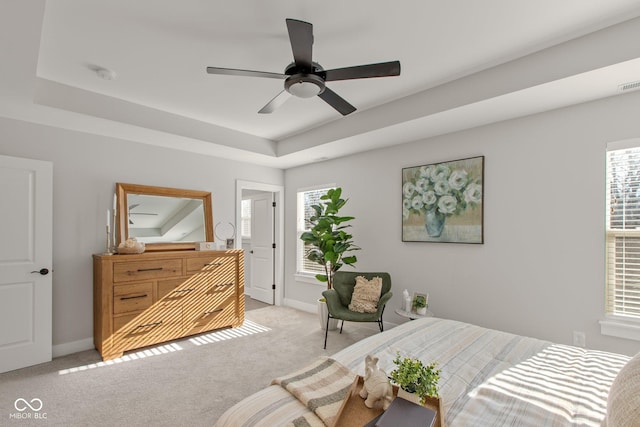 carpeted bedroom featuring ceiling fan and a raised ceiling