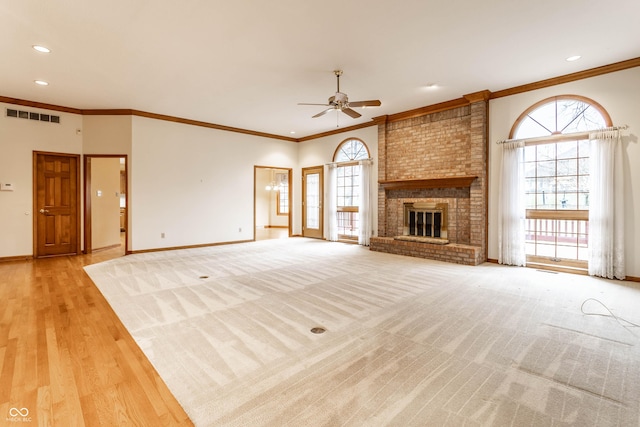 unfurnished living room featuring ceiling fan, light wood-type flooring, ornamental molding, and a brick fireplace