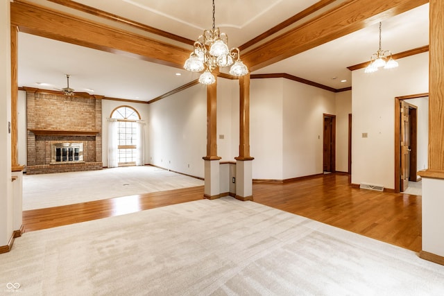 unfurnished living room featuring ornamental molding, ceiling fan with notable chandelier, beamed ceiling, a fireplace, and hardwood / wood-style floors