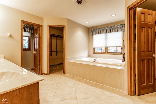 bathroom featuring tile patterned flooring, vanity, and tiled tub