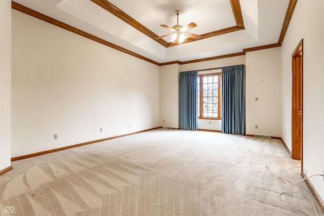 spare room with ceiling fan, light colored carpet, ornamental molding, and a tray ceiling