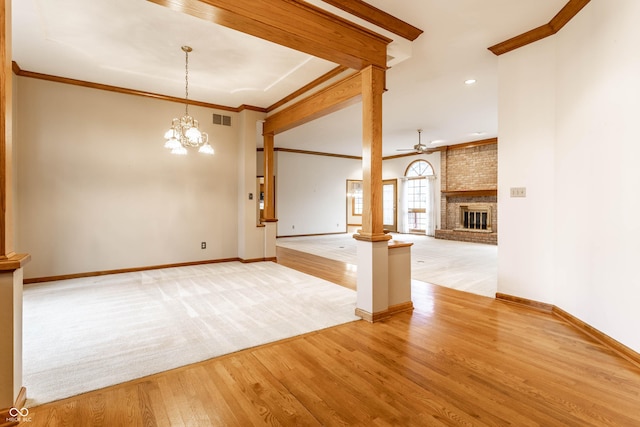 unfurnished living room with a brick fireplace, ornamental molding, ceiling fan with notable chandelier, and light wood-type flooring