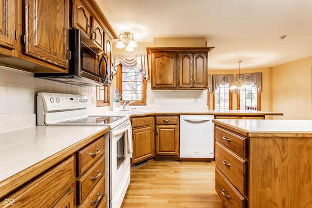 kitchen featuring white appliances, light hardwood / wood-style flooring, a wealth of natural light, and an inviting chandelier