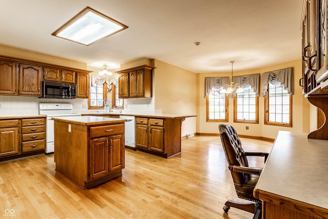 kitchen featuring decorative light fixtures, a kitchen island, white appliances, and a chandelier