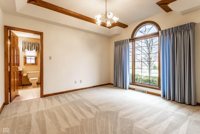 spare room with light colored carpet, plenty of natural light, and a notable chandelier