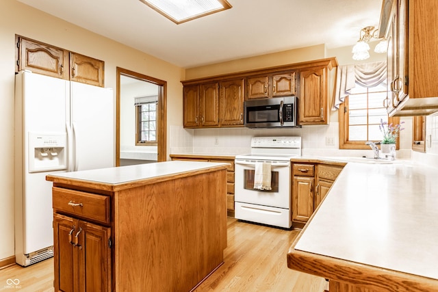 kitchen with light hardwood / wood-style floors, plenty of natural light, a center island, and white appliances