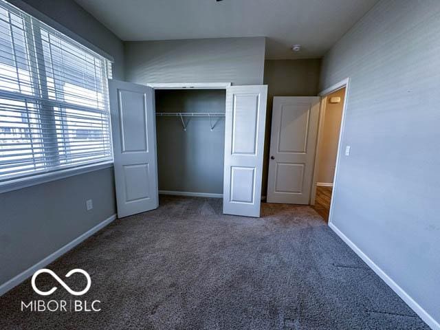 unfurnished bedroom featuring dark colored carpet and a closet