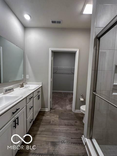 bathroom featuring vanity, toilet, an enclosed shower, and wood-type flooring