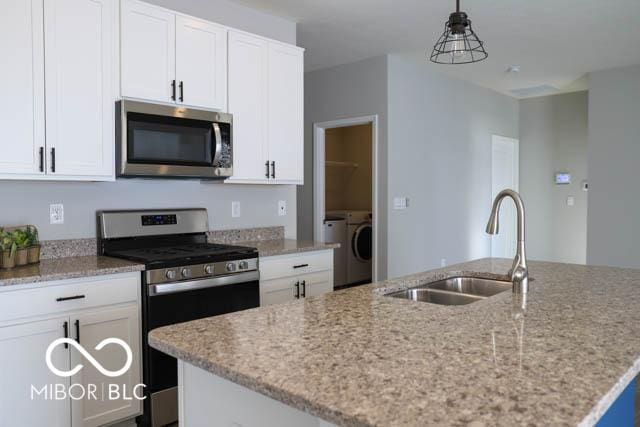 kitchen with white cabinetry, sink, hanging light fixtures, a center island with sink, and appliances with stainless steel finishes