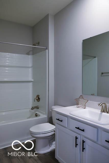 full bathroom featuring hardwood / wood-style floors, vanity, toilet, and shower / washtub combination