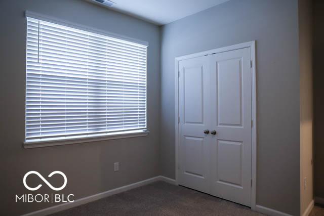 unfurnished bedroom with dark carpet and a closet