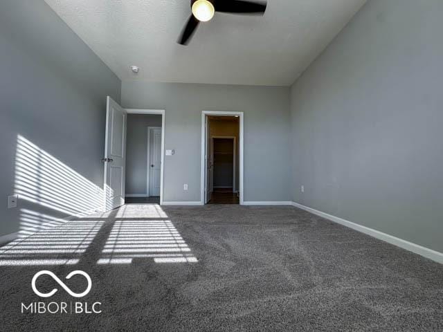 interior space with ceiling fan and dark carpet