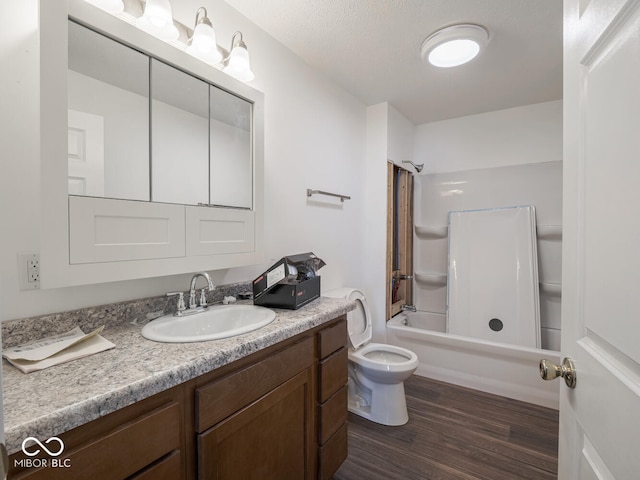 full bathroom with vanity, shower / washtub combination, hardwood / wood-style flooring, toilet, and a textured ceiling