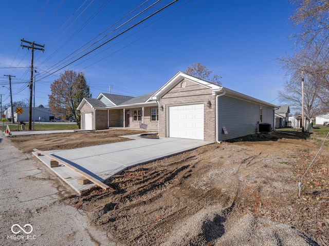 ranch-style home with central air condition unit and a garage