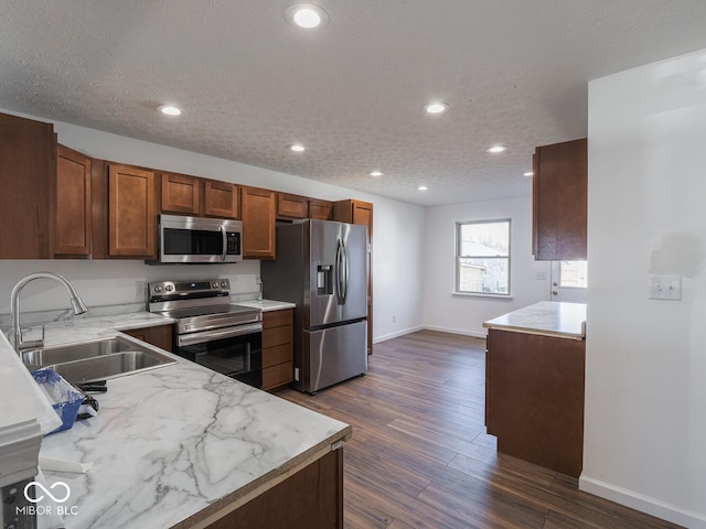 kitchen featuring appliances with stainless steel finishes, a textured ceiling, dark hardwood / wood-style floors, and sink