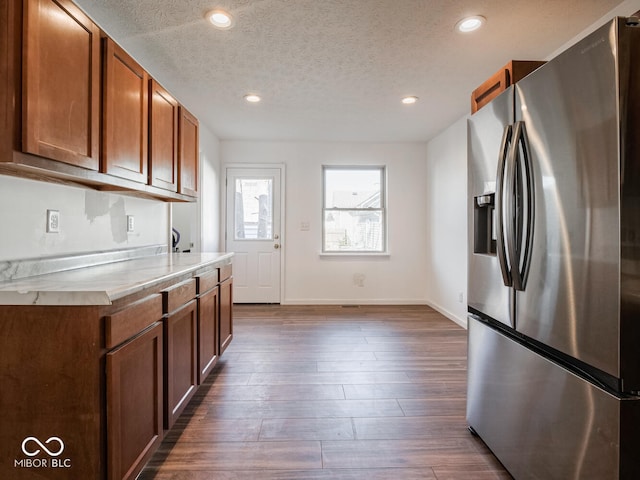 kitchen with stainless steel fridge, dark wood-type flooring, and a textured ceiling