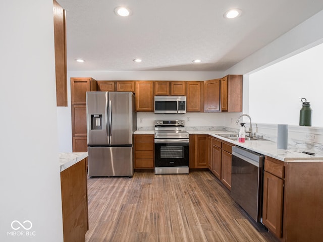 kitchen featuring light stone counters, sink, stainless steel appliances, and hardwood / wood-style flooring