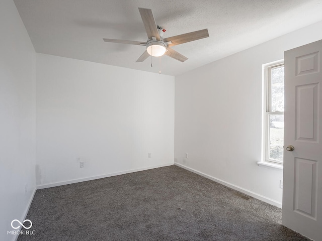 unfurnished room with ceiling fan, dark carpet, and a textured ceiling