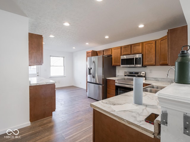 kitchen featuring kitchen peninsula, appliances with stainless steel finishes, dark hardwood / wood-style flooring, a textured ceiling, and sink