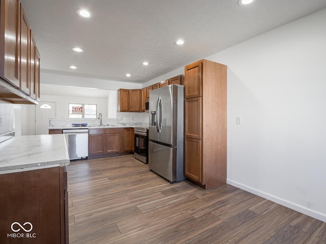 kitchen featuring sink, light stone countertops, dark wood-type flooring, and appliances with stainless steel finishes