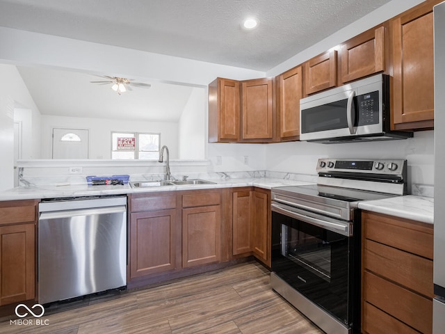 kitchen featuring dark hardwood / wood-style flooring, a textured ceiling, stainless steel appliances, vaulted ceiling, and sink