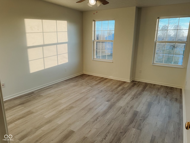 unfurnished room with ceiling fan, a wealth of natural light, and light wood-type flooring