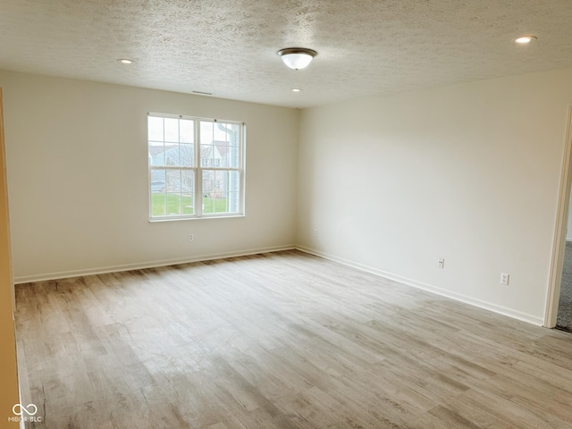 empty room featuring light hardwood / wood-style floors and a textured ceiling