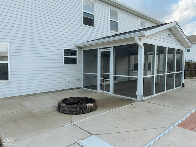 rear view of house with a patio, a sunroom, and a fire pit