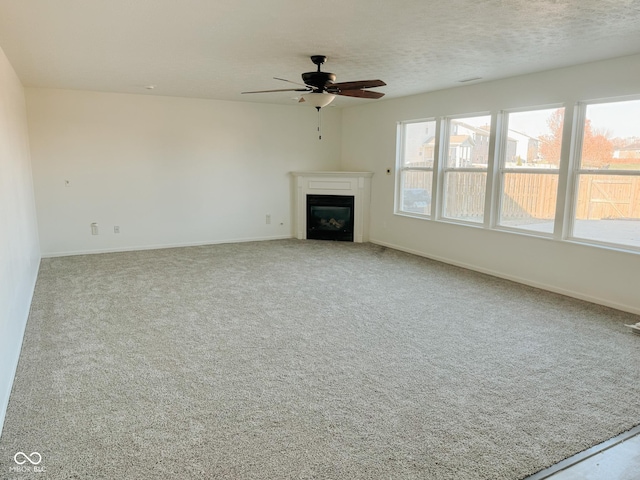 unfurnished living room with light carpet, ceiling fan, and a textured ceiling