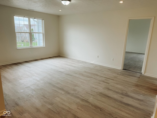 unfurnished room featuring light hardwood / wood-style floors and a textured ceiling