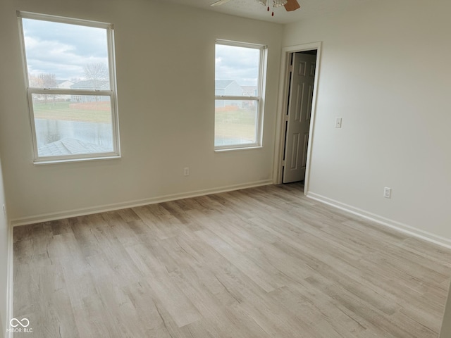 empty room with ceiling fan and light hardwood / wood-style flooring