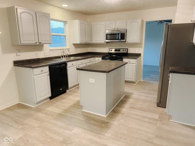 kitchen featuring sink, appliances with stainless steel finishes, a center island, light hardwood / wood-style floors, and white cabinets