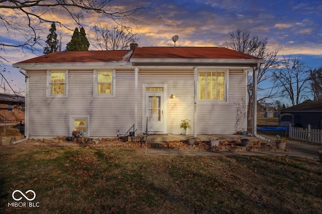 back house at dusk with a lawn