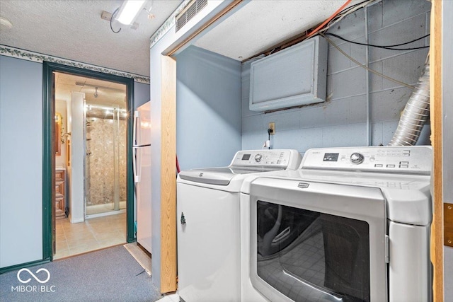 laundry area featuring light tile patterned floors, a textured ceiling, and separate washer and dryer